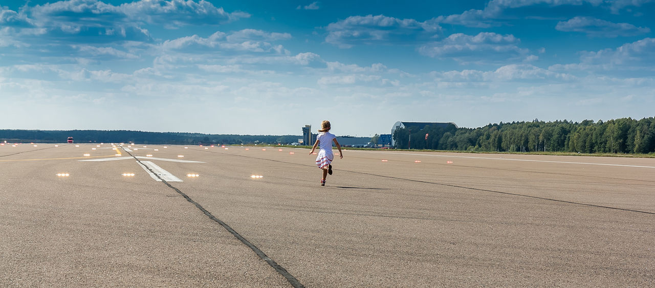 Rear view full length of girl running at airport runway