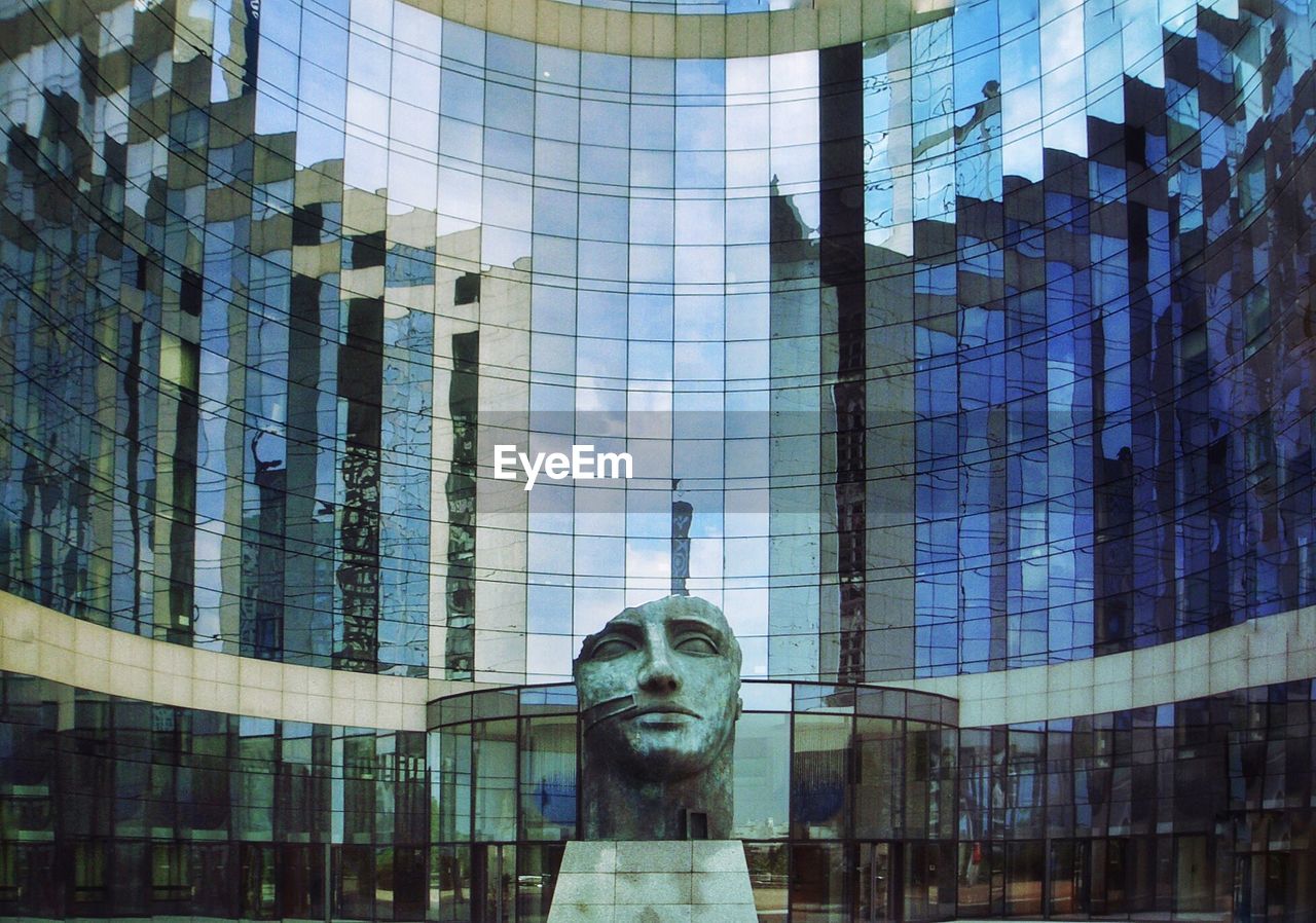 Reflection of statue in modern glass building