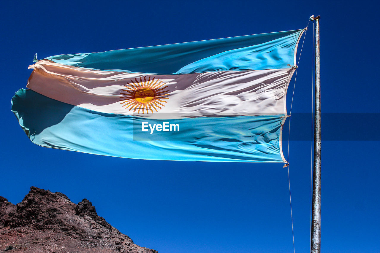 Low angle view of argentinian flag against clear blue sky