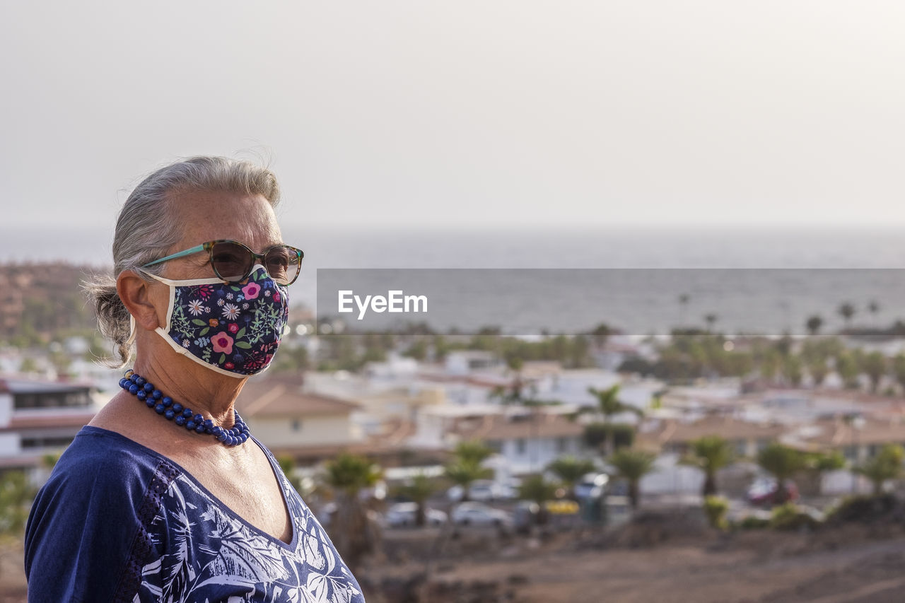 Close-up of senior woman wearing mask standing outdoors