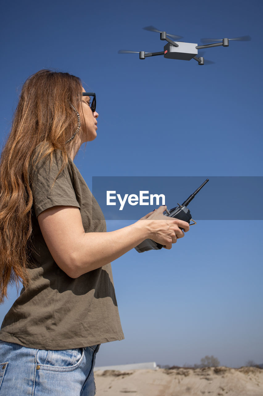 WOMAN HOLDING CAMERA AGAINST SKY