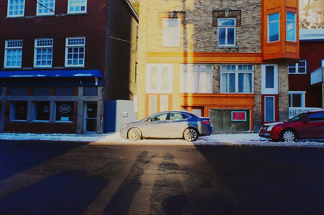 Cars parked in front of building covered with snow