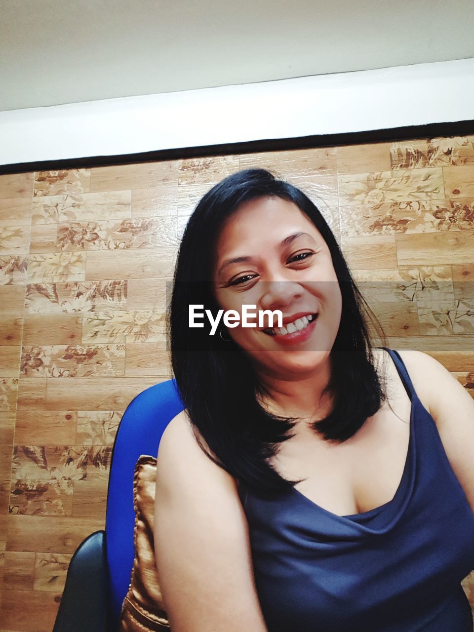 Smiling woman sitting on chair against wall