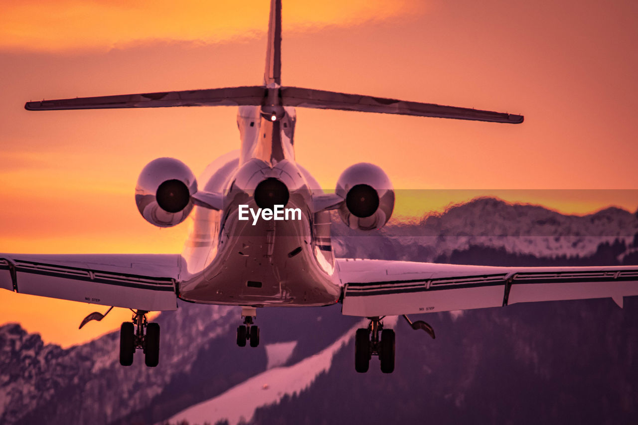 Airplane flying against sky during sunset