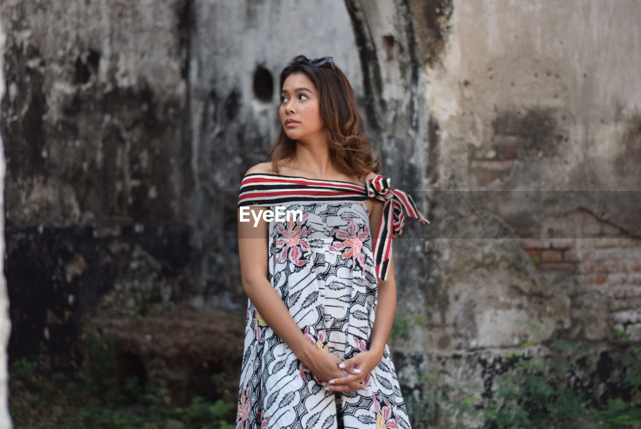 BEAUTIFUL WOMAN STANDING AGAINST WALL