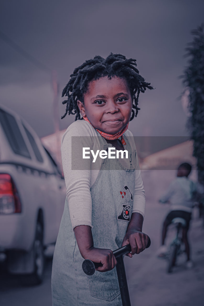 Portrait of smiling girl by car outdoors