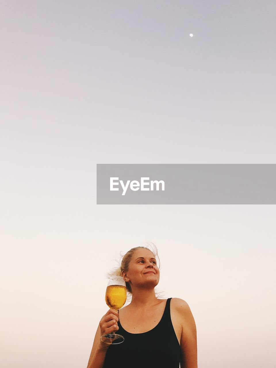 Thoughtful woman having wine against clear sky during sunset