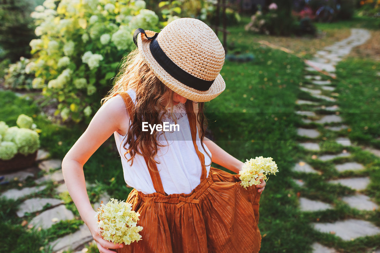 Girl holding flowers while standing in yard