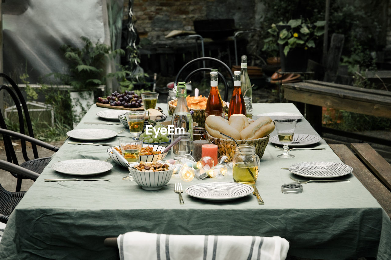 Food and drink set up with plates arranged on dining table in back yard