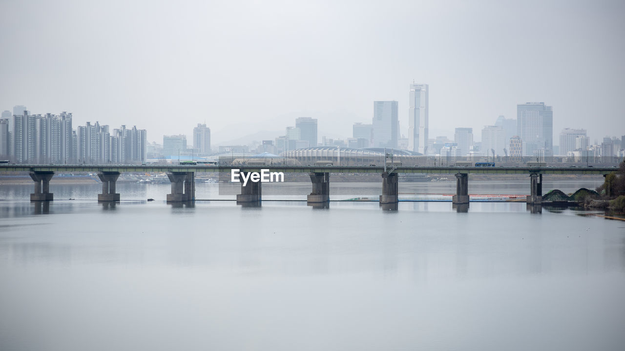 bridge over river in city against clear sky