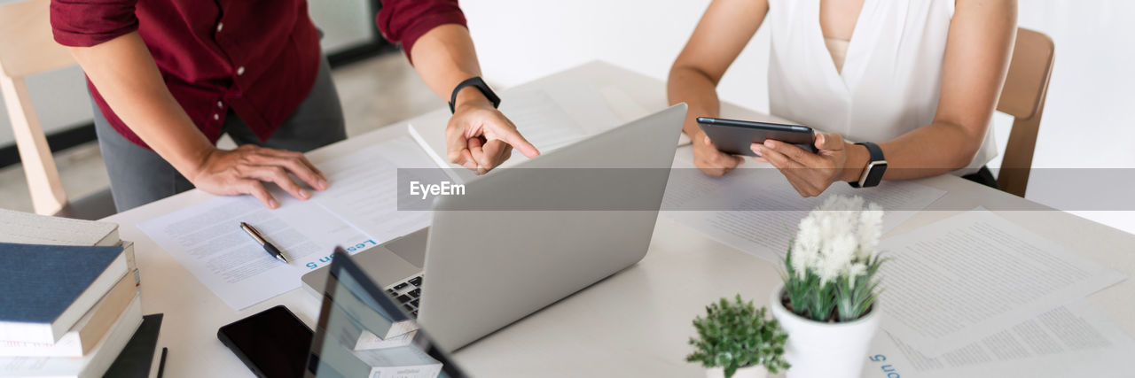 REAR VIEW OF PEOPLE WORKING ON TABLE AT HOME