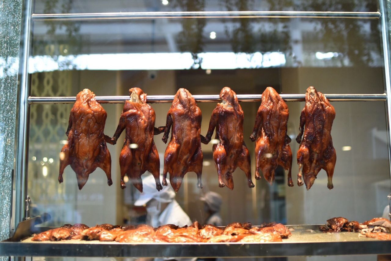 Close-up of roasted meat hanging on rod in commercial kitchen