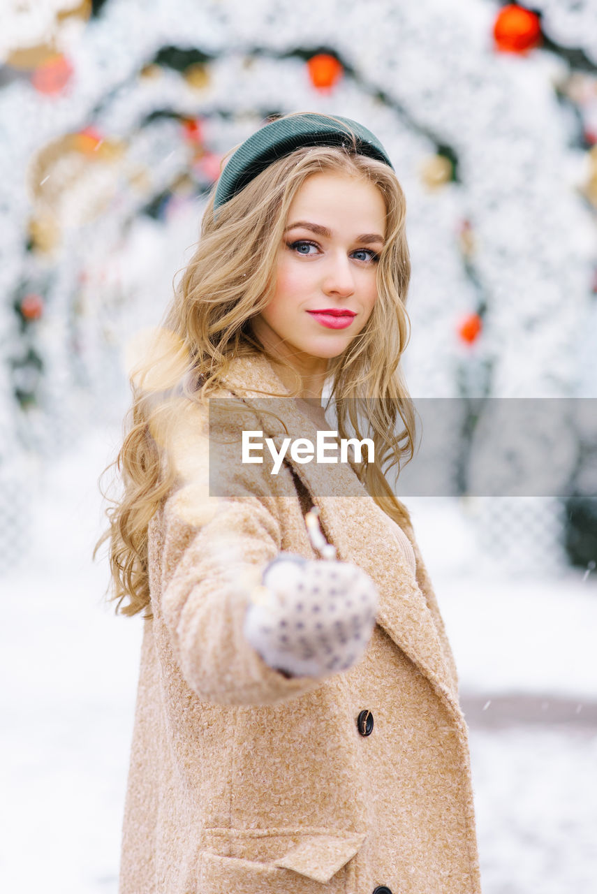 Follow me concept photo of a young girl at a christmas market holding a garland