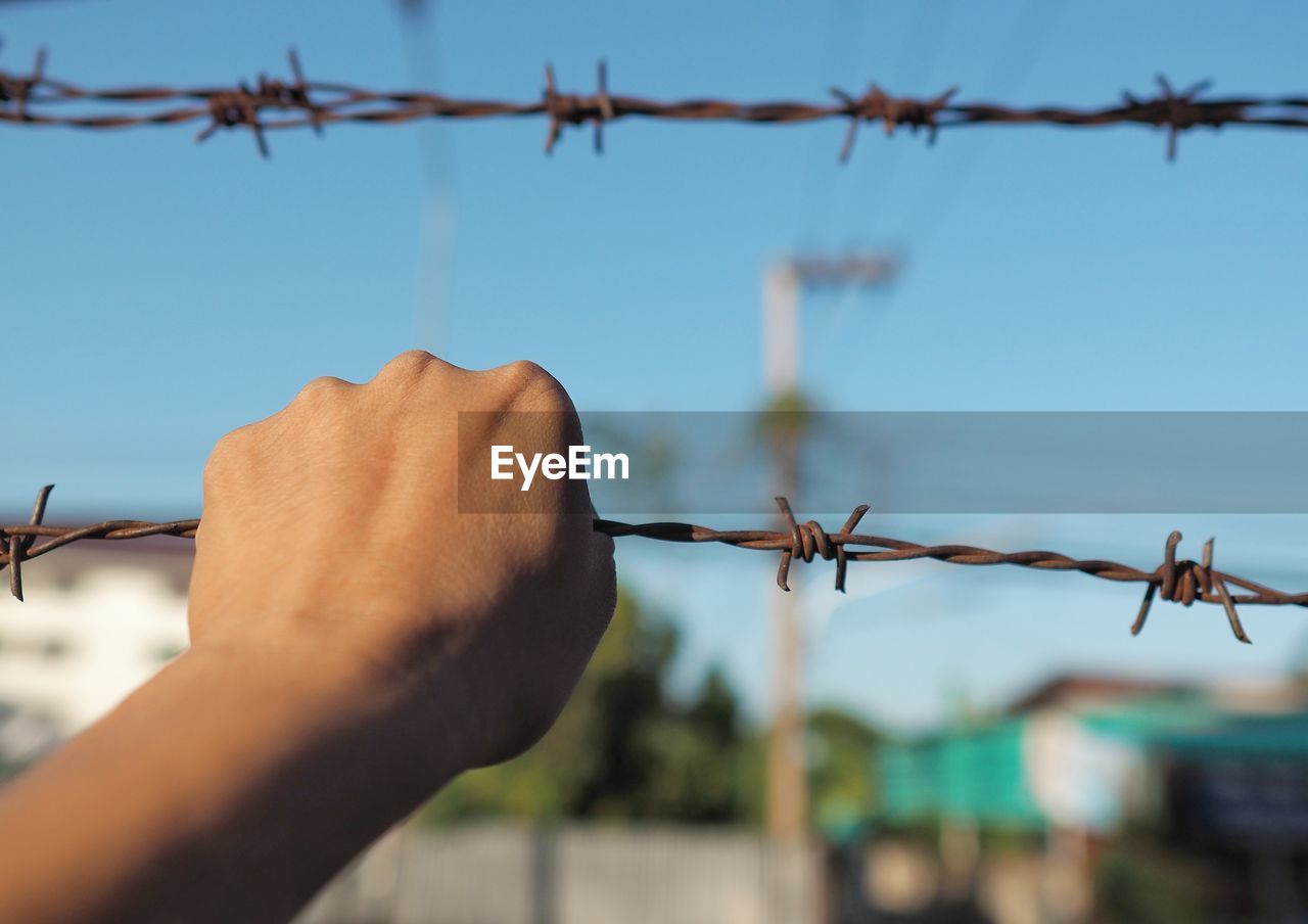 Close-up of barbed wire fence against sky