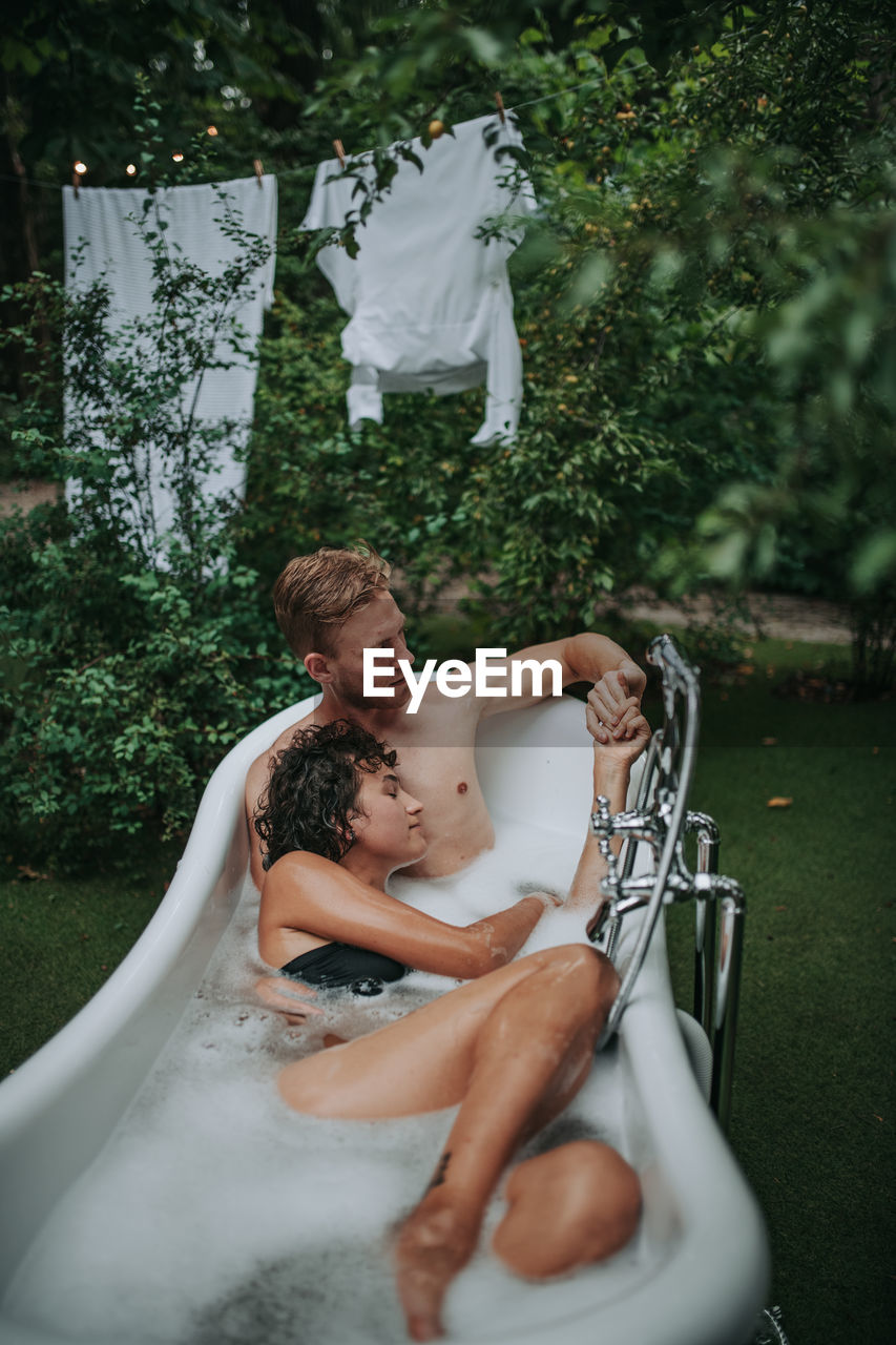 Midsection of couple looking at woman sitting outdoors