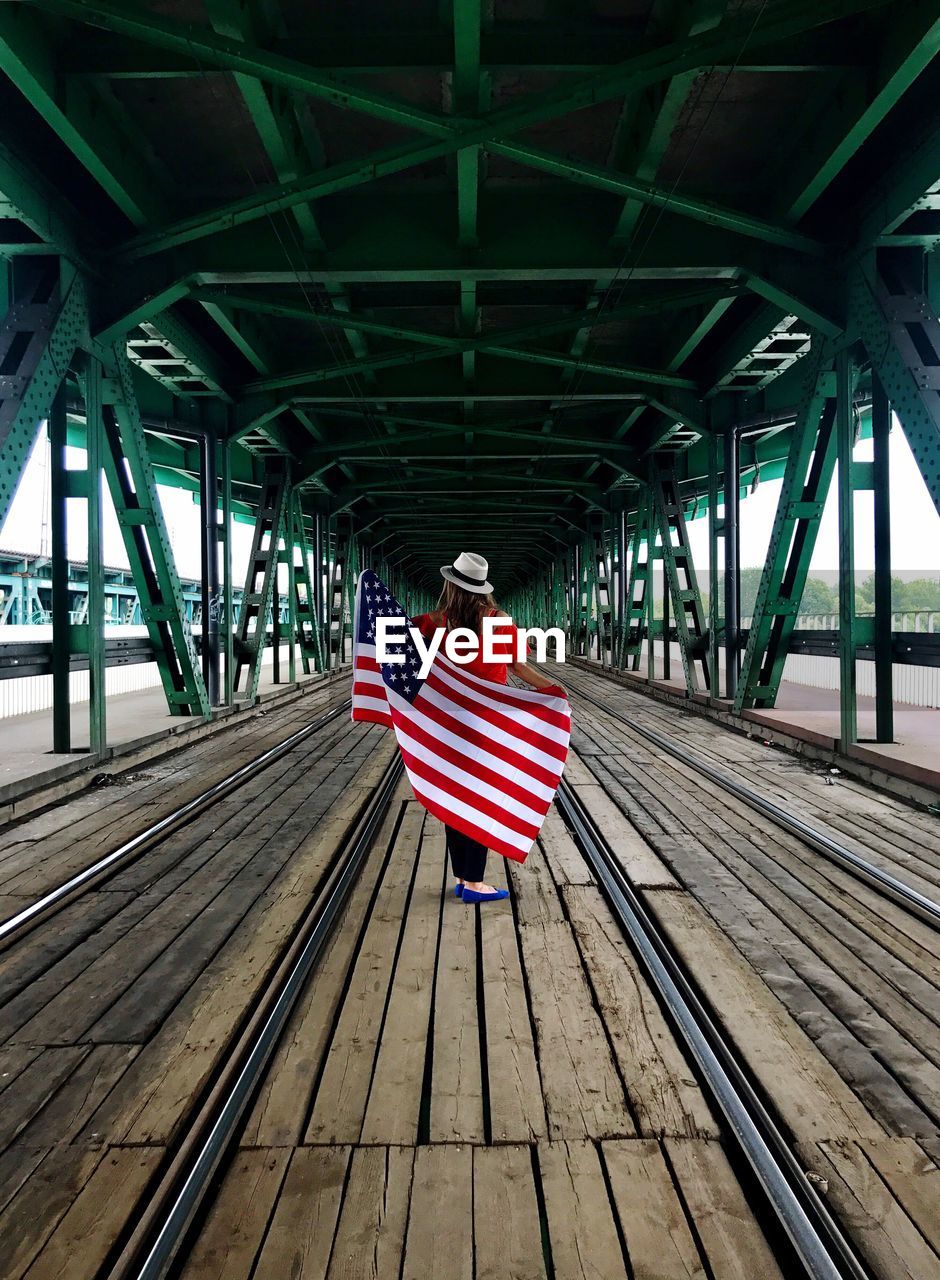 Rear view of woman standing on bridge 