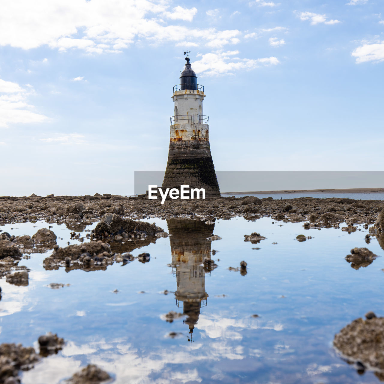 Lighthouse by sea against sky