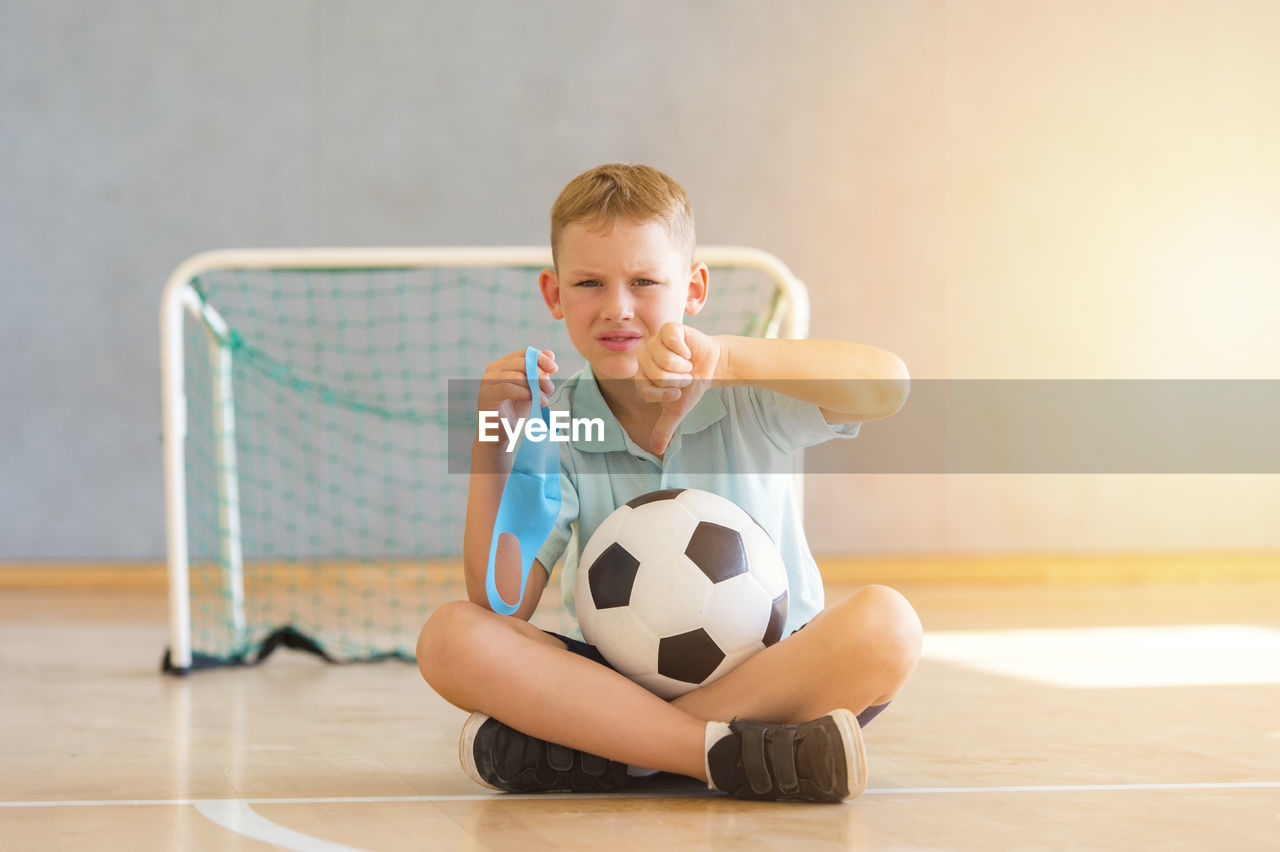Portrait of smiling boy with ball on floor