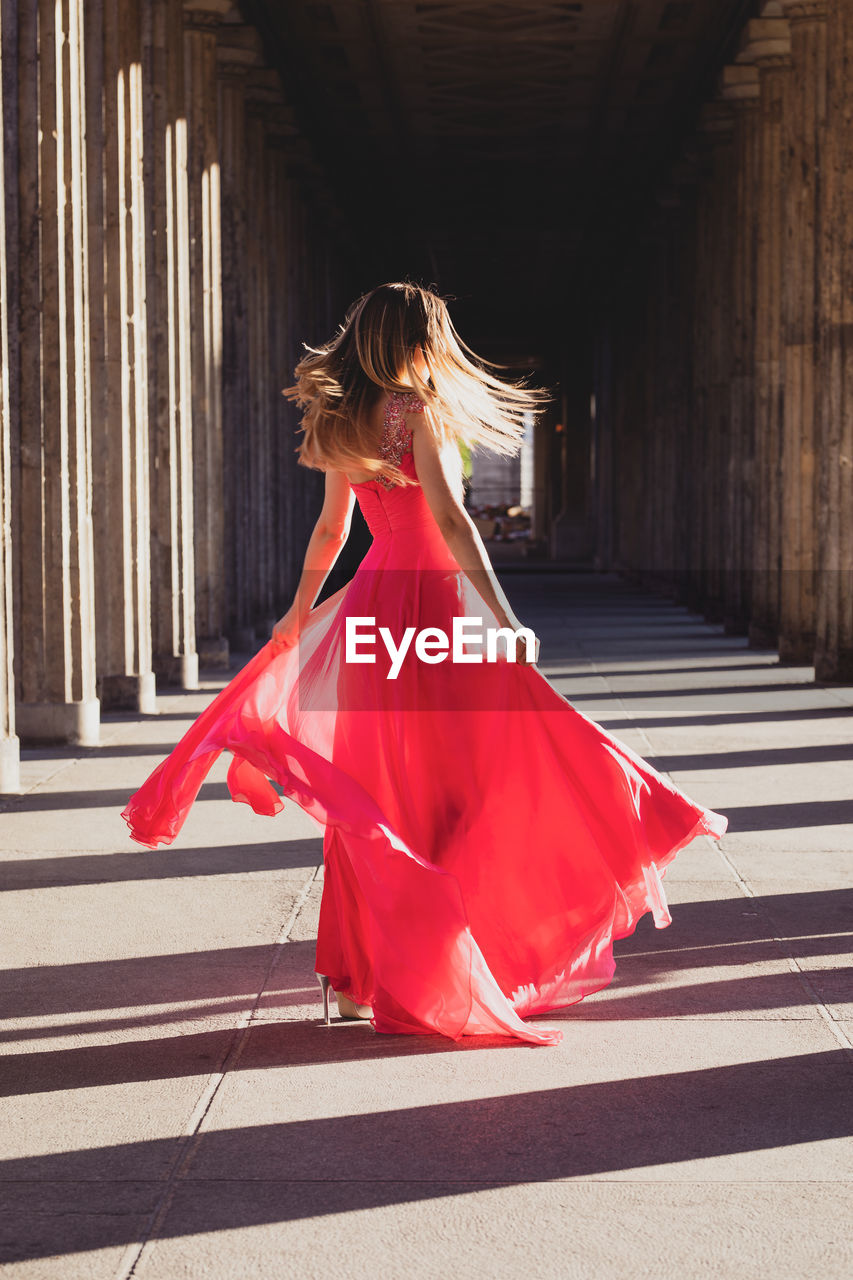 Woman wearing red dress while dancing in corridor