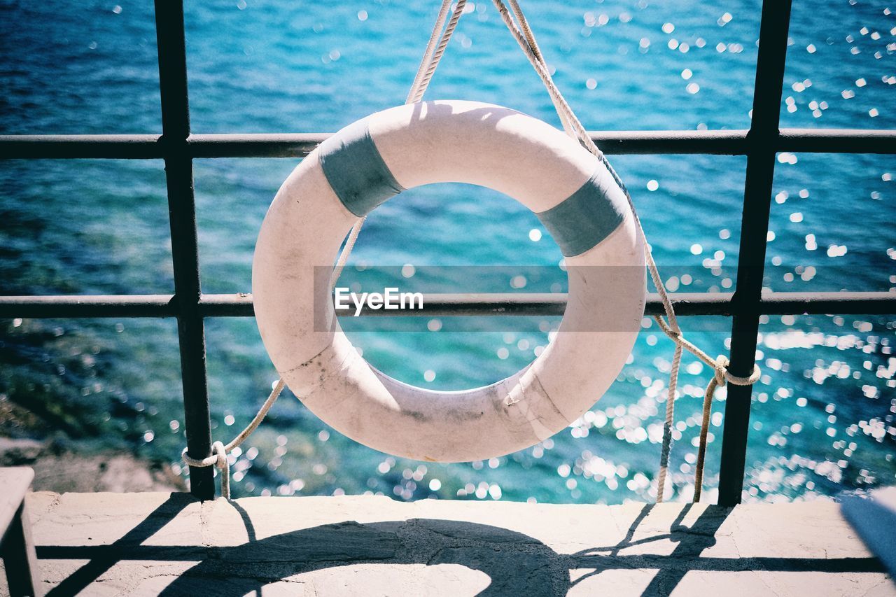 High angle view of white inflatable ring hanging from railing on pier against sea
