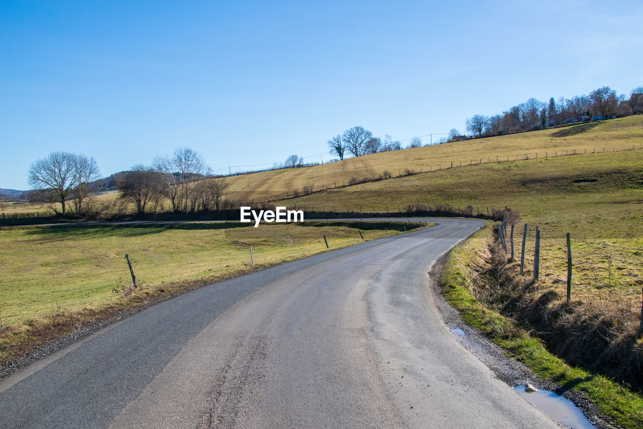 ROAD PASSING THROUGH FIELD AGAINST SKY