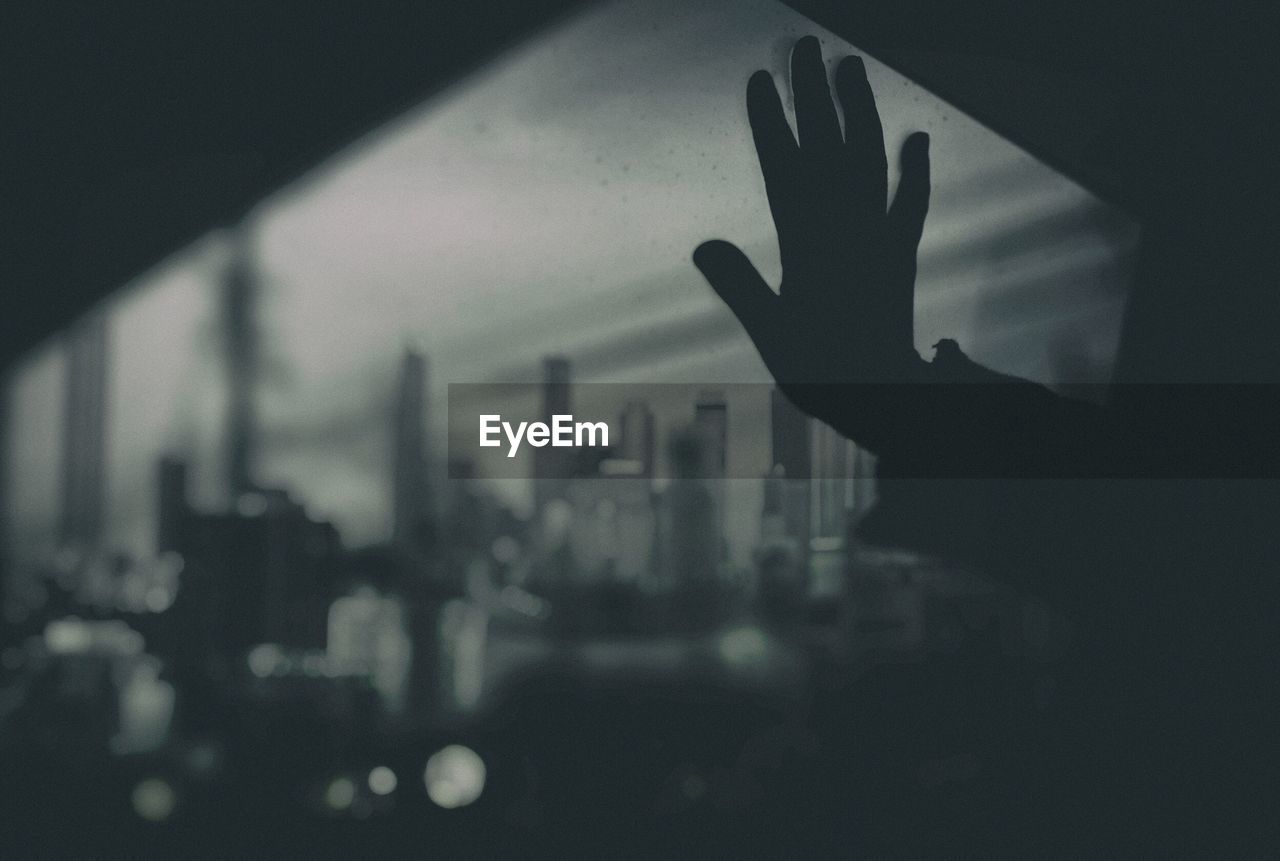 CLOSE-UP OF SILHOUETTE HAND ON GLASS