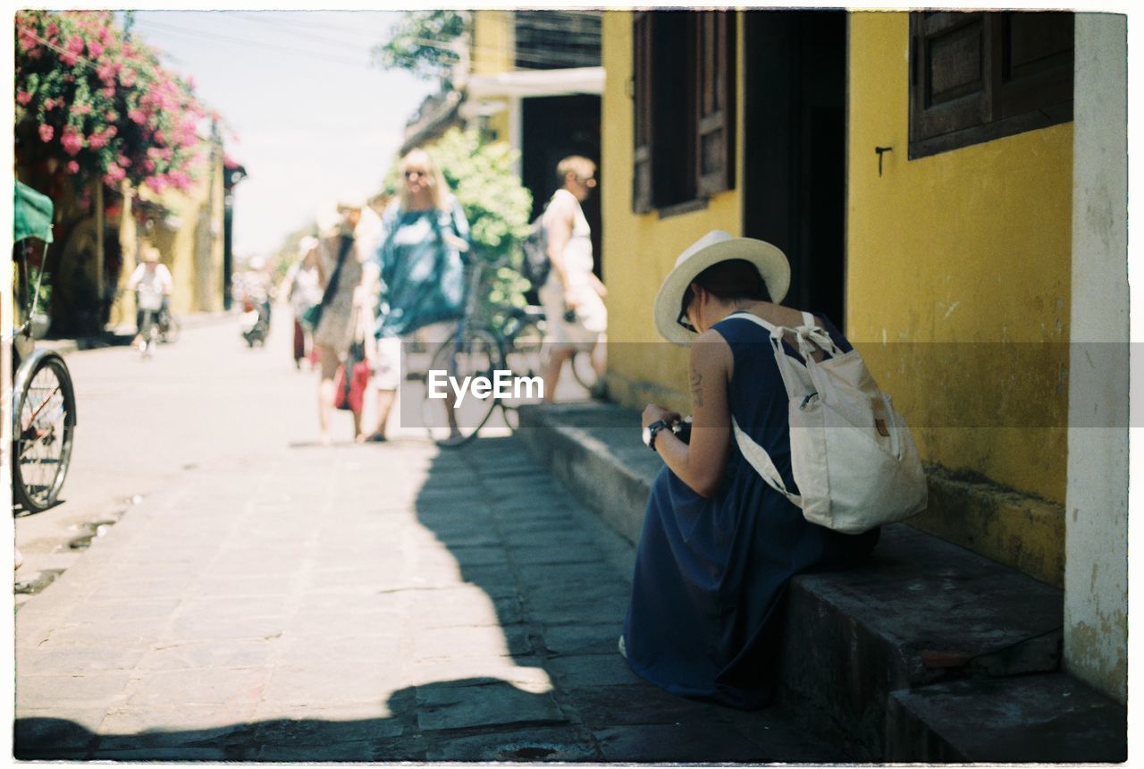 Rear view of woman sitting by house in city