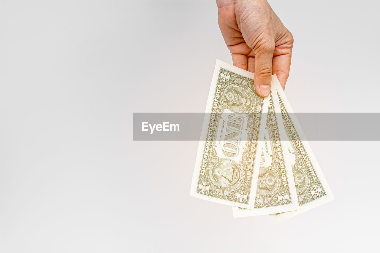 Close-up of hand holding currency on white background