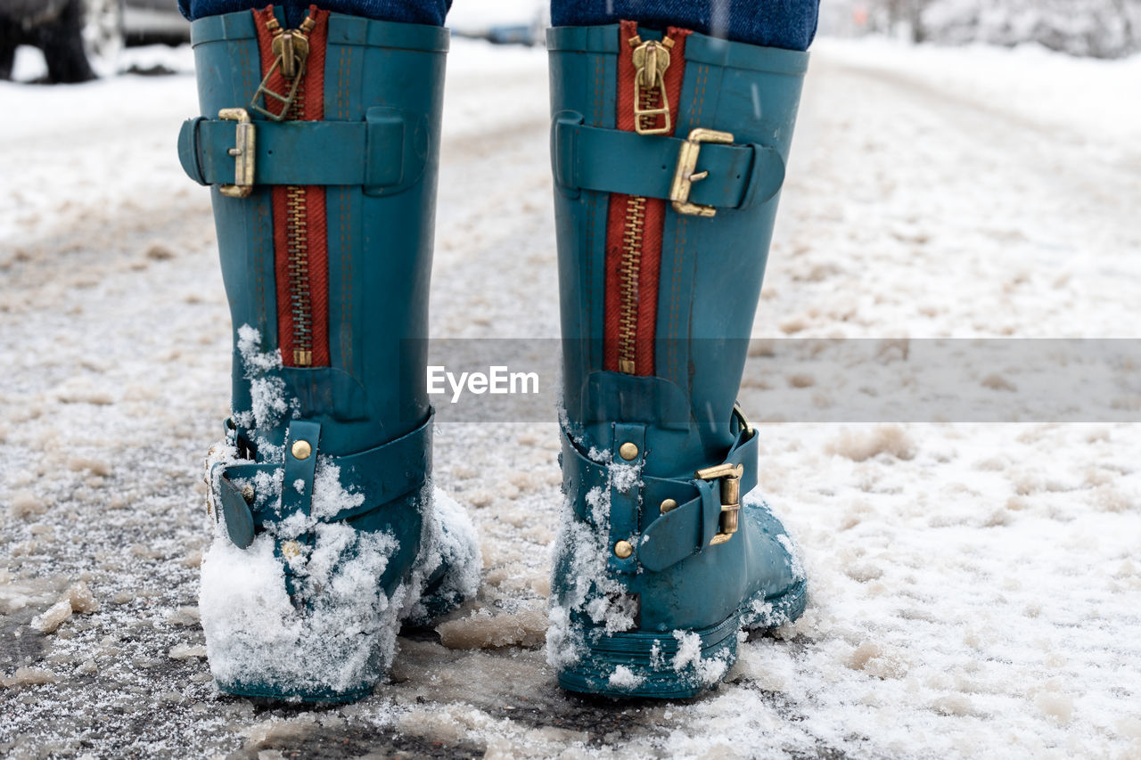 Snowy and slippery roads. woman in rubber boots