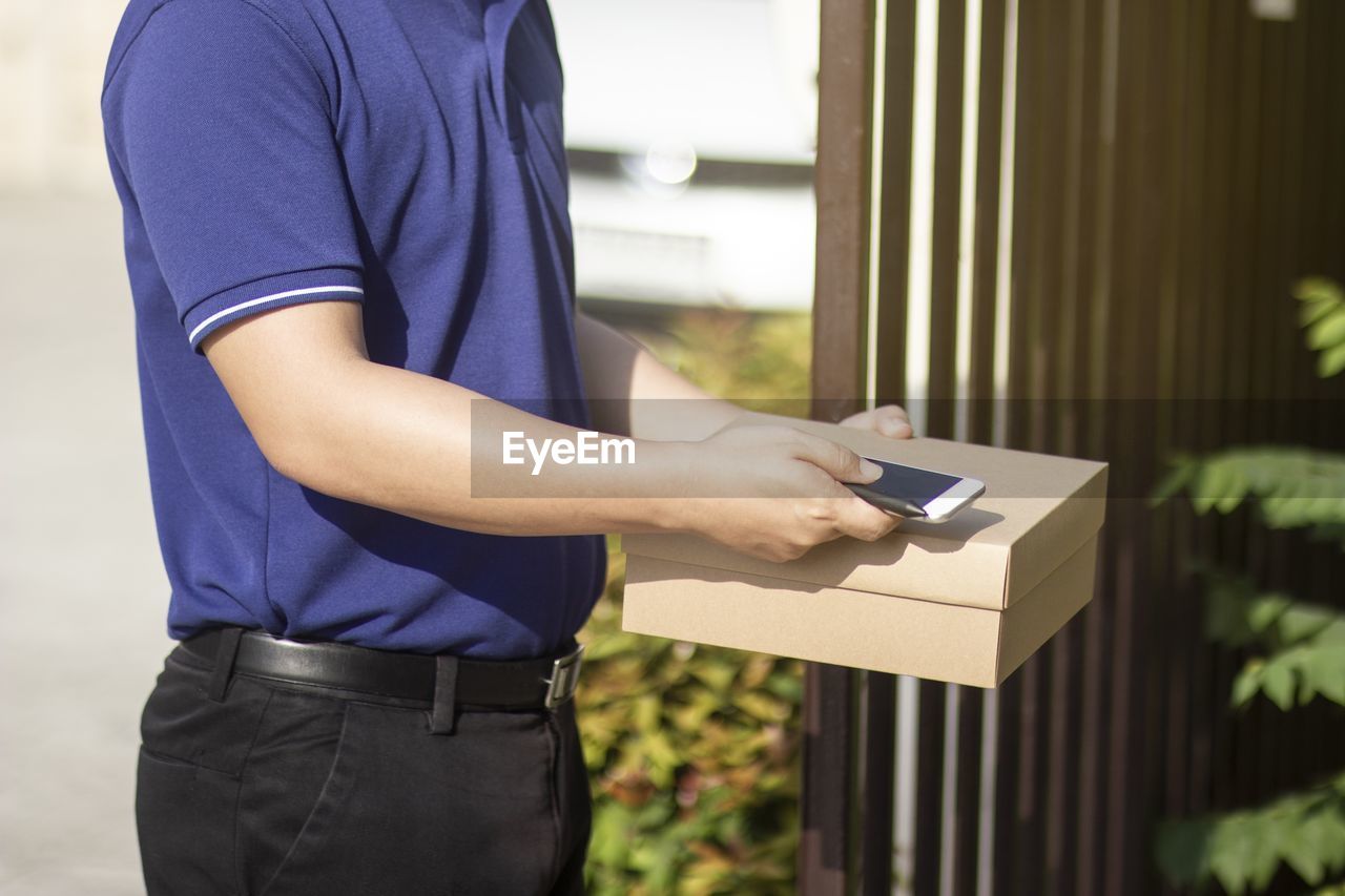 MIDSECTION OF MAN HOLDING SMART PHONE