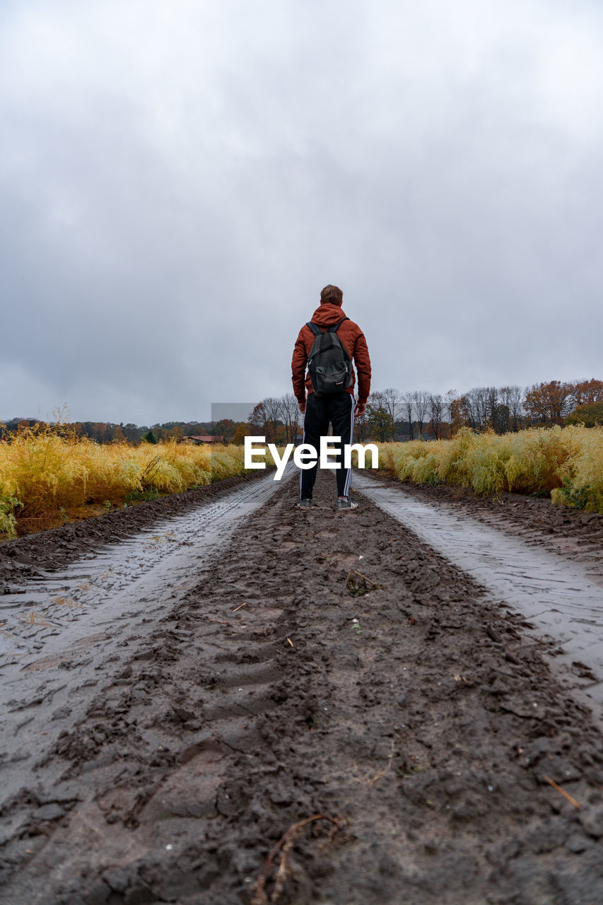 Rear view of man standing on road against sky