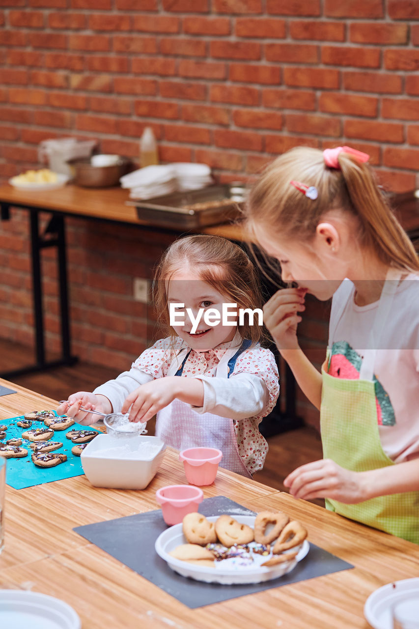 PORTRAIT OF MOTHER AND GIRL HAVING BREAKFAST