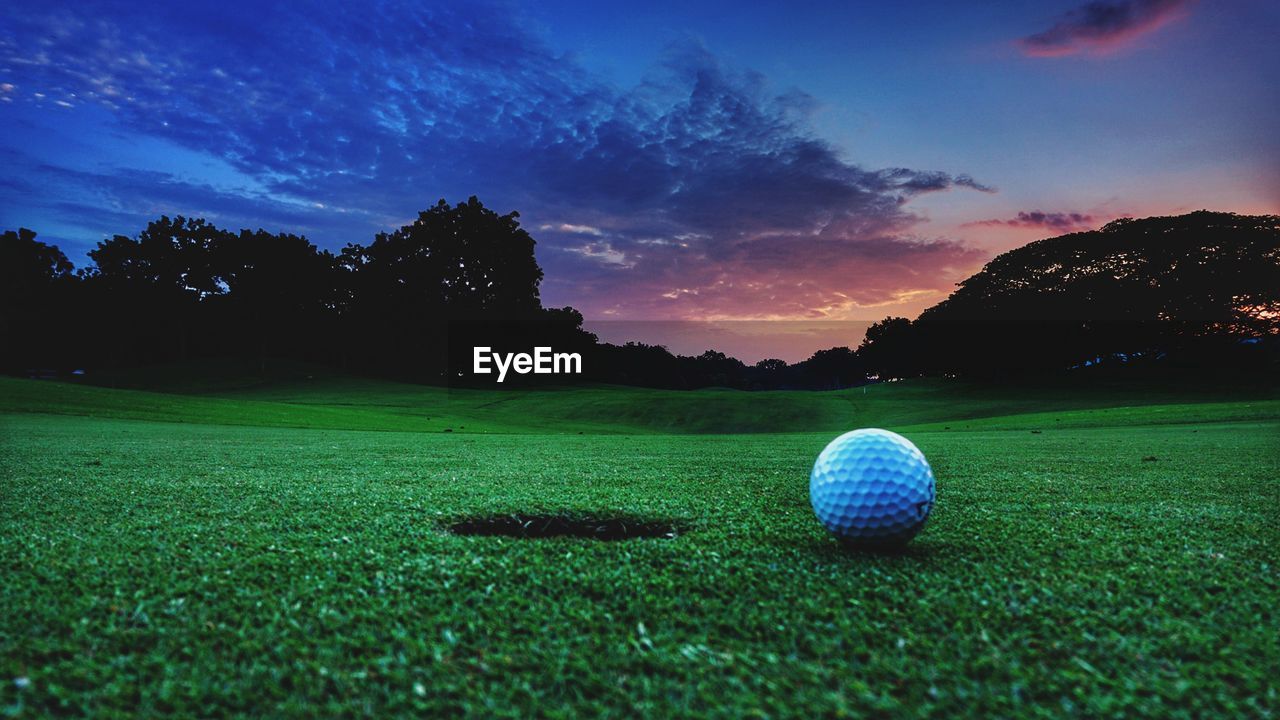 Ball on golf course against sky during sunset