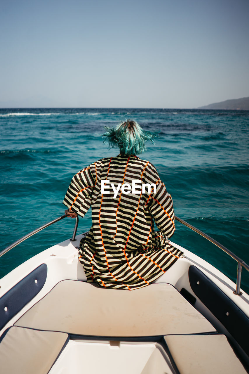 rear view of woman sitting on boat in sea against sky