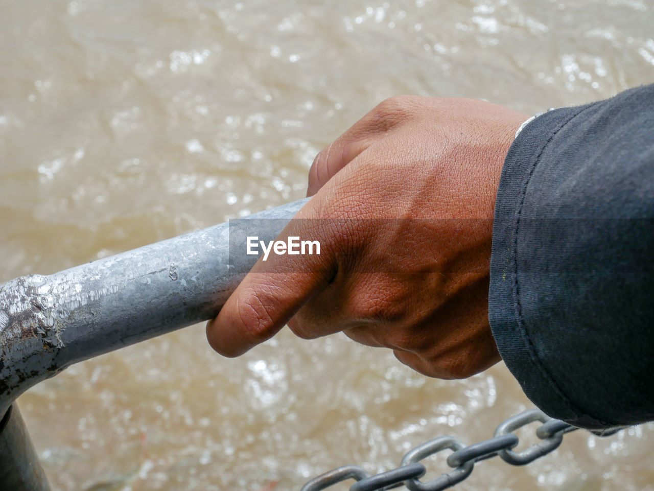 Close-up of hand holding railing against sea
