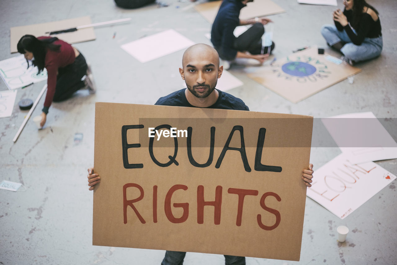 Bald man with equal rights sign standing in building