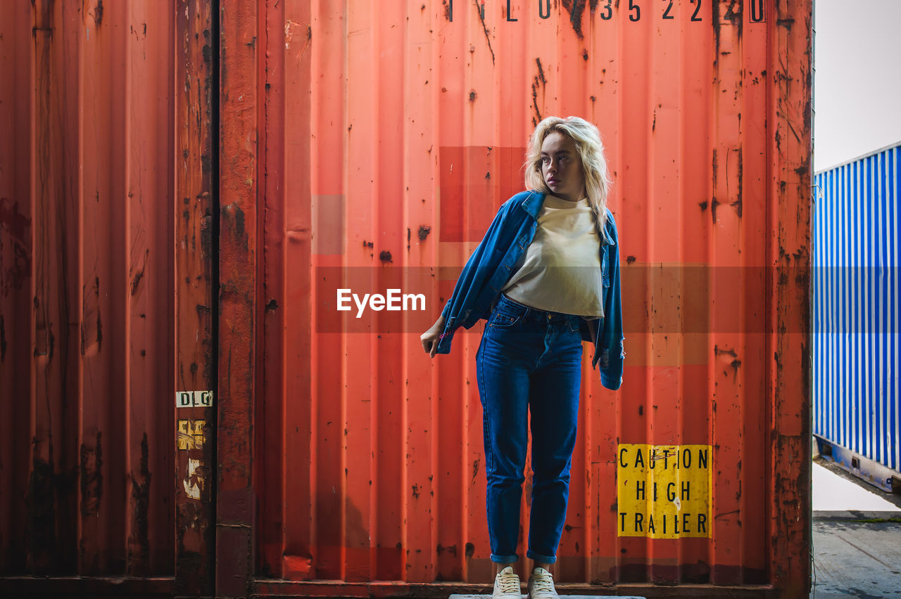 Woman standing against cargo container