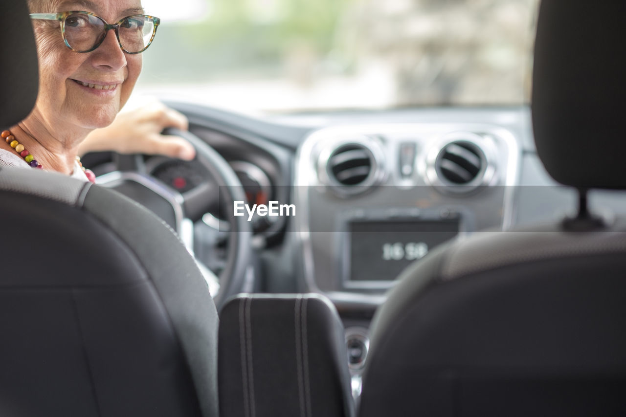 Portrait of smiling senior woman sitting in car