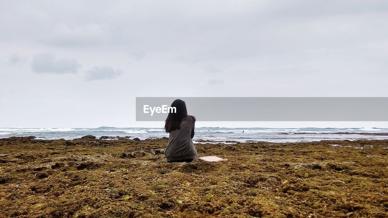 Rear sight of woman sitting on the beach