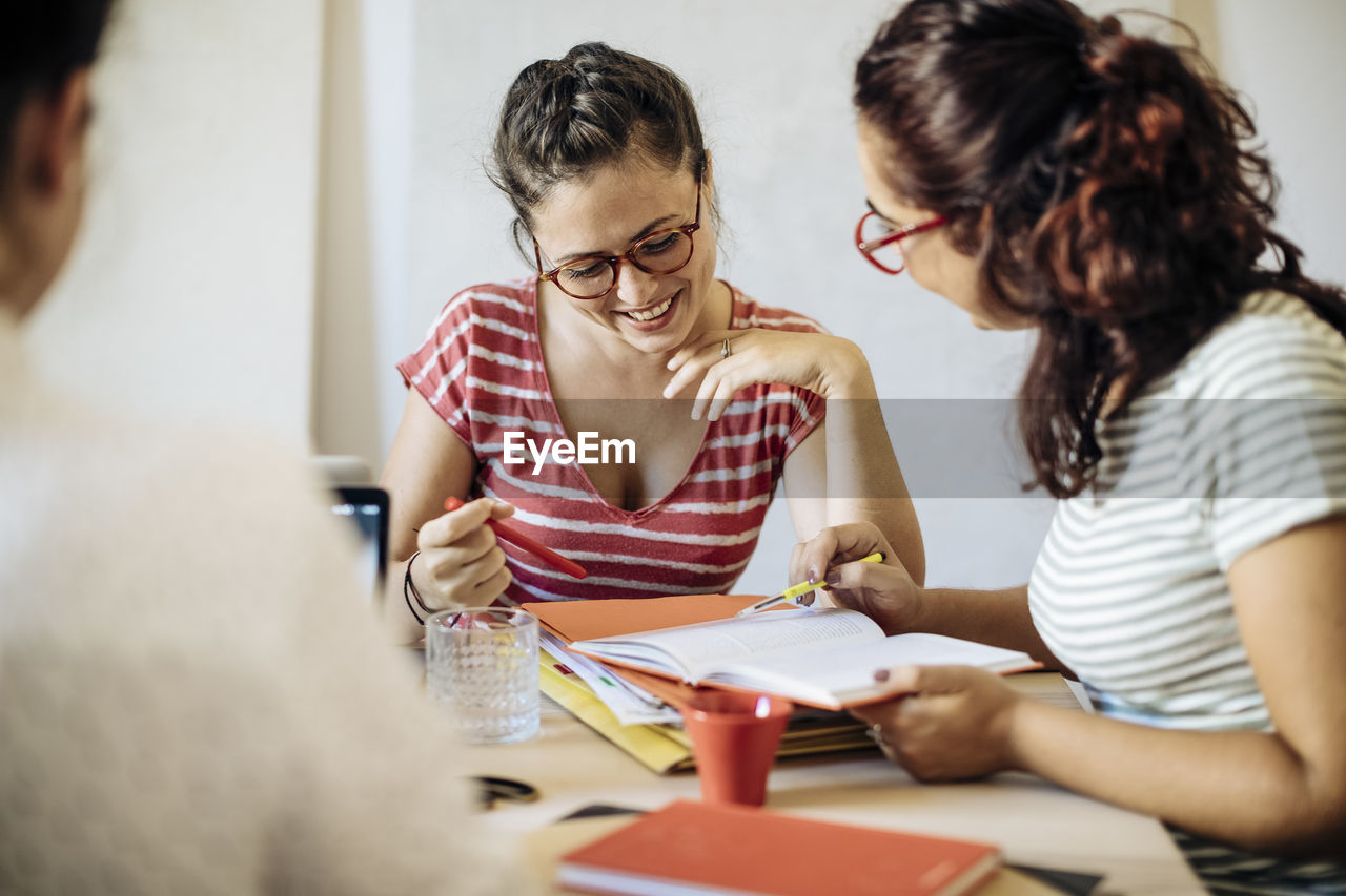 Smiling casual women discussing business strategies at desk