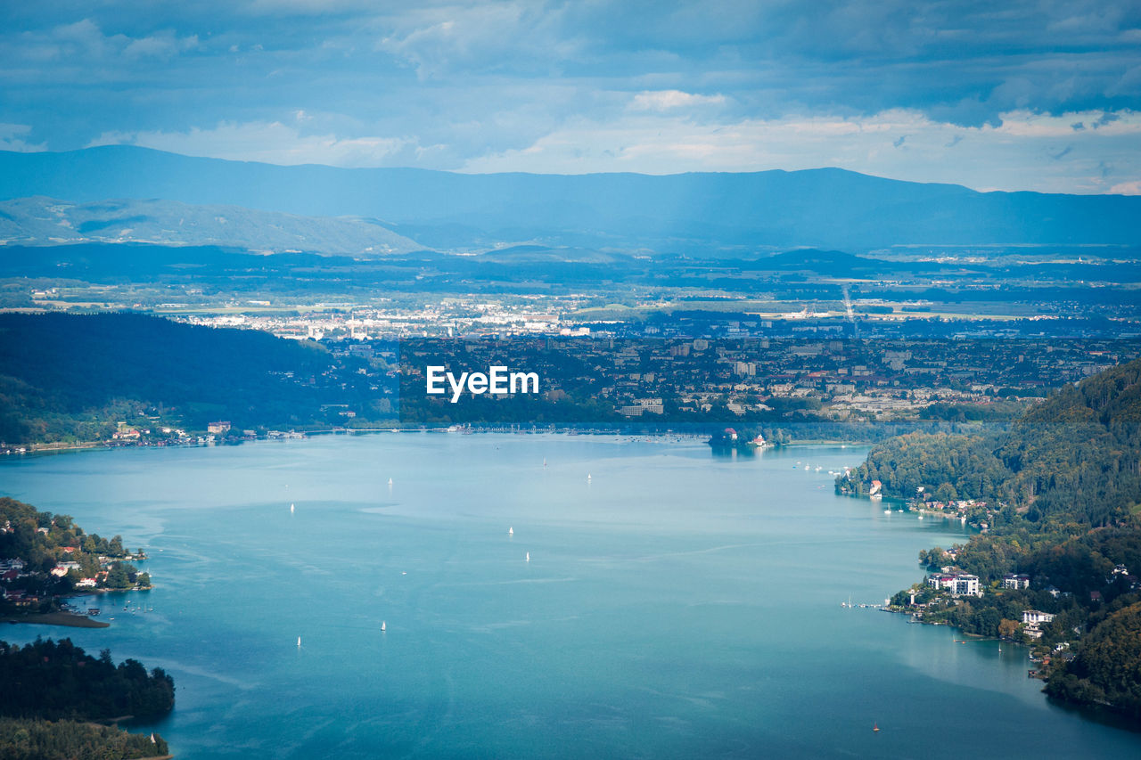 Aerial view of sea by town against sky