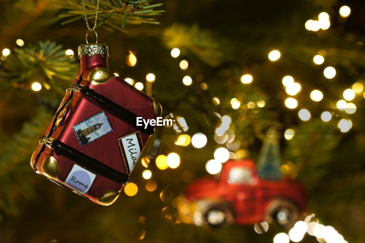  suitcase bauble hanging at christmas tree against christmas lights 