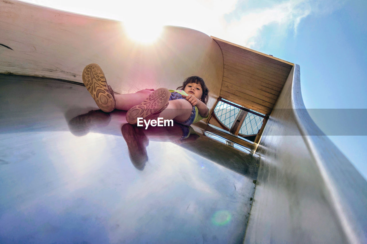 Low angle view of cute girl on slide against sky