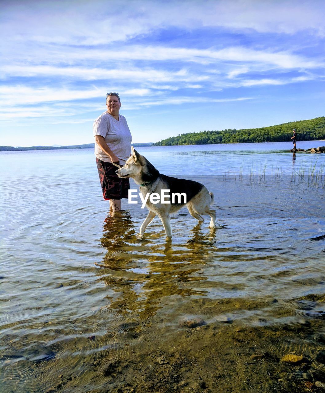Woman standing with dog in lake against sky