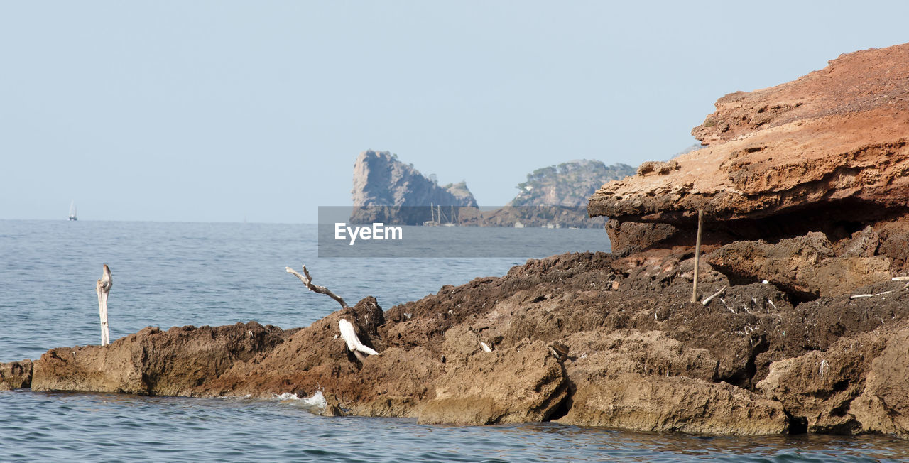 VIEW OF SEAGULL ON ROCK FORMATION AGAINST SEA