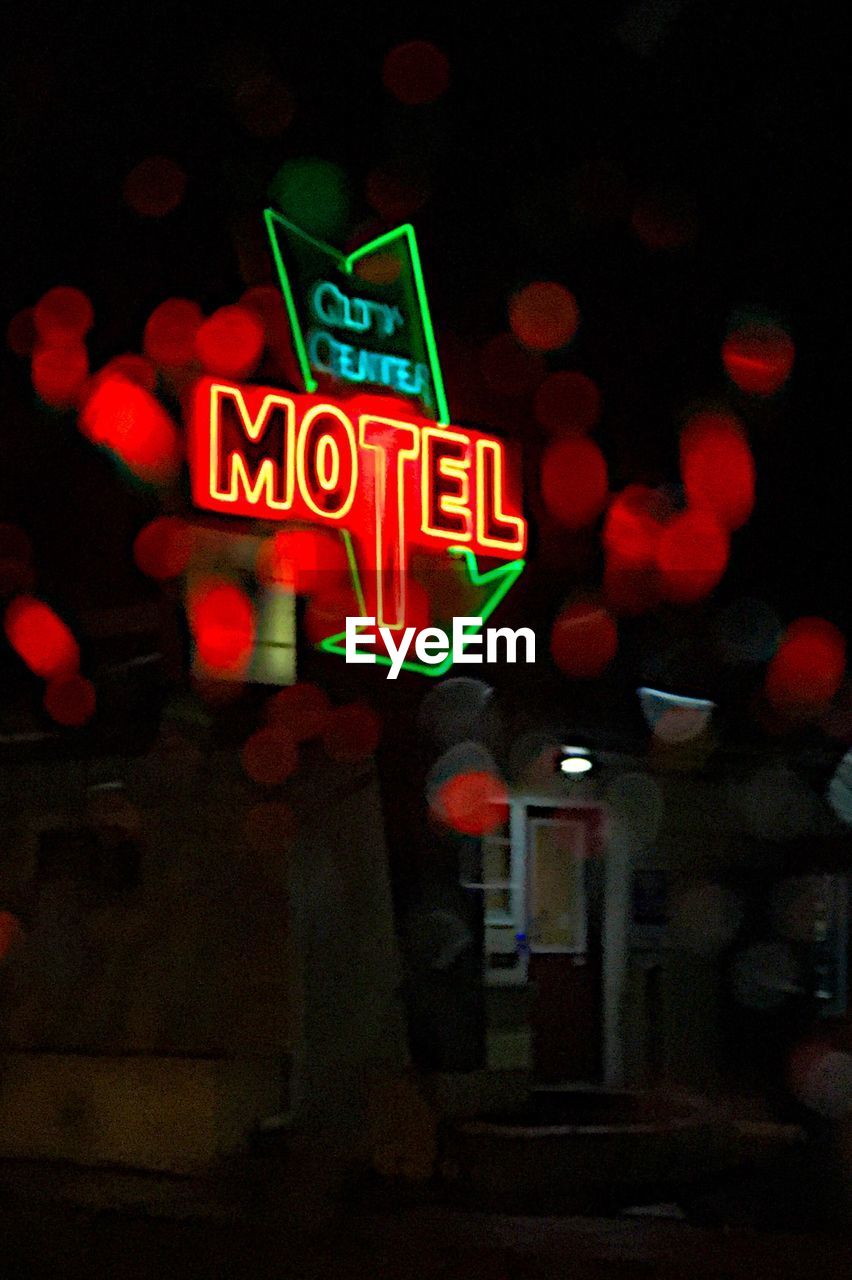 Low angle view of illuminated motel sign at night