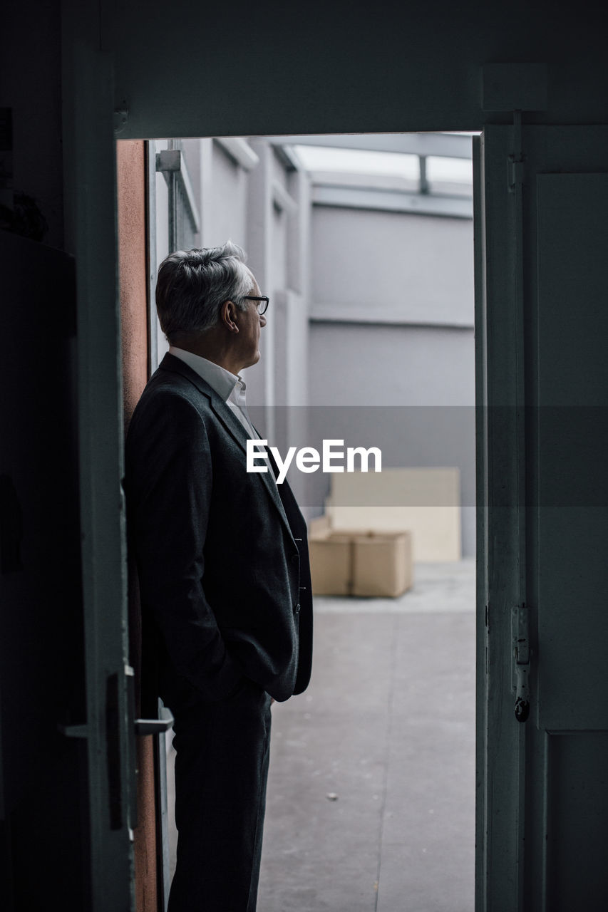 Senior businessman standing in door frame