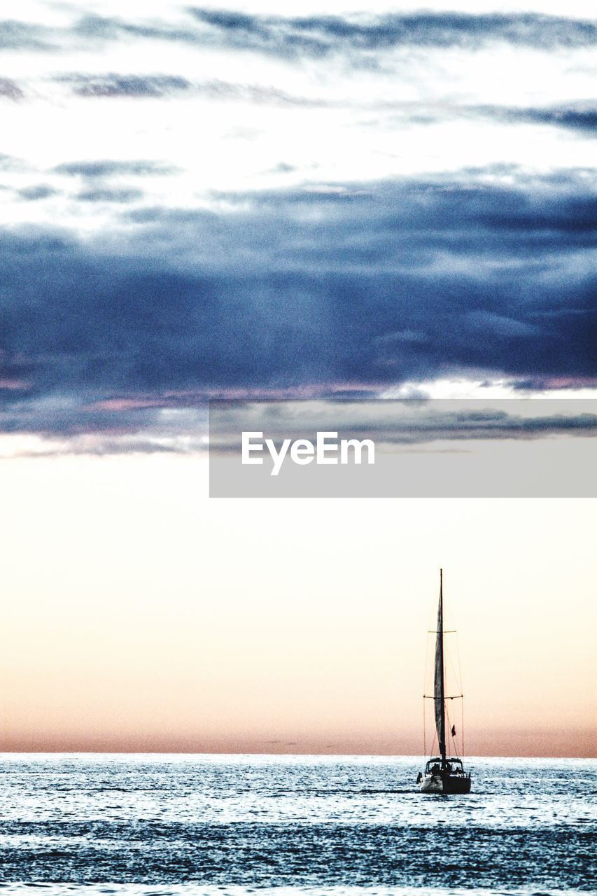Sailboat sailing on sea against sky during sunset