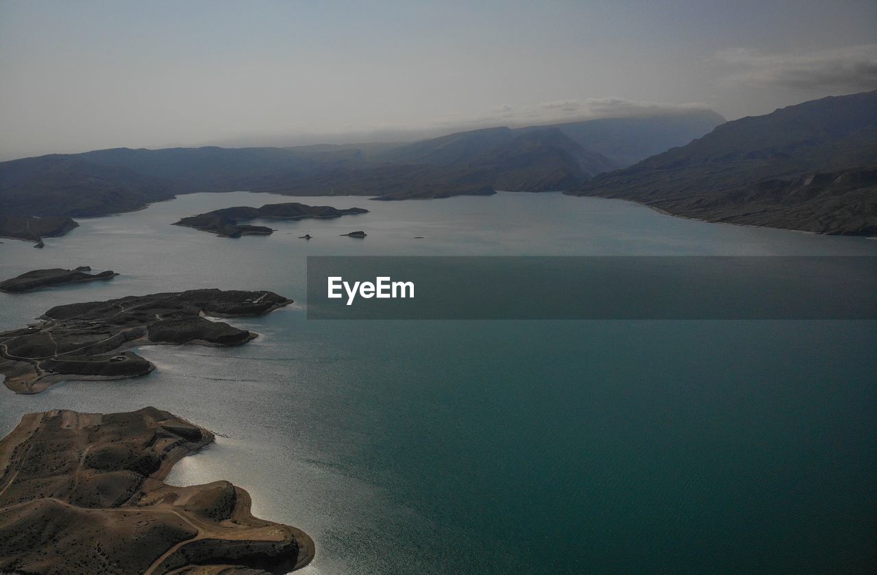 SCENIC VIEW OF SEA BY MOUNTAINS AGAINST SKY