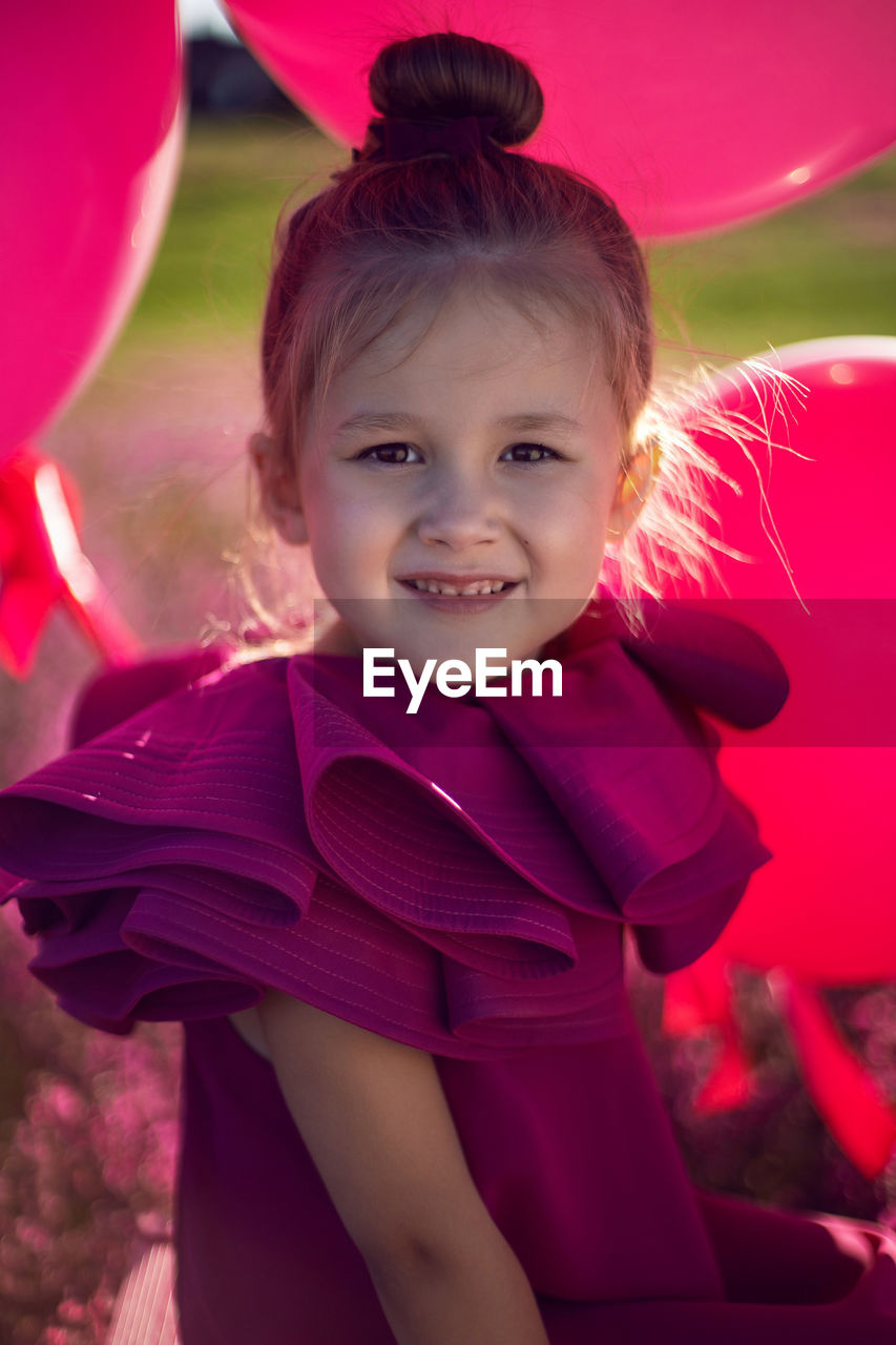  girl child of 5 years old is sitting on a pink stepladder,  dress in a field with pink flowers